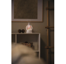 Lanterne de Noël à eau avec éclairage LED et paillettes sur une étagère blanche dans une ambiance de Noël.