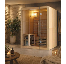 Sauna d intérieur en bois avec façade et porte en verre dans un espace bien-être lumineux avec mur en pierre naturelle, plante et accessoires.