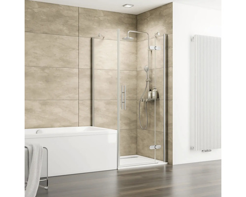 Salle de bain moderne avec cabine de douche en verre, baignoire blanche, carrelage mural beige aspect pierre et radiateur vertical blanc.