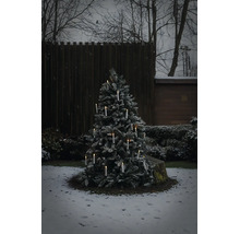 Verschneiter Weihnachtsbaum im Aussenbereich mit leuchtenden kabellosen LED Kerzen in einem winterlichen Garten.