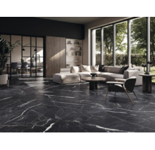 Salon moderne avec carrelage de sol sombre aspect marbre et veinures blanches, canapé clair et grandes baies vitrées.