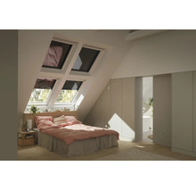 Chambre lumineuse sous combles avec quatre fenêtres de toit, lit avec linge rose, armoires encastrées et vue sur une salle de bains.