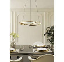 Suspension LED moderne dorée en forme de vague au-dessus d'une table à manger dressée dans une salle à manger lumineuse.