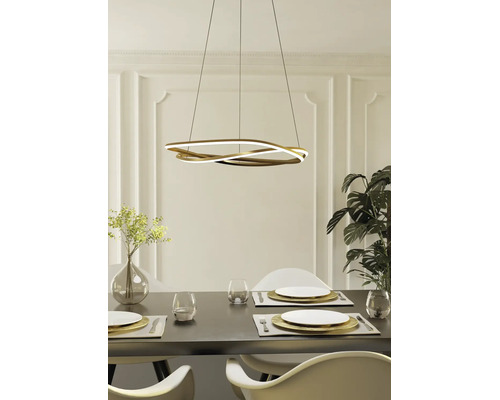 Suspension LED moderne dorée en forme de vague au-dessus d'une table à manger dressée dans une salle à manger lumineuse.