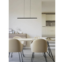 Suspension LED linéaire noire au-dessus d'une table en bois clair avec chaises beiges dans une salle à manger minimaliste.