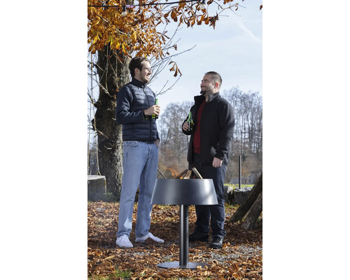 Zwei Männer stehen im herbstlichen Garten an einer modernen, brennenden Feuerschale aus Metall und unterhalten sich.