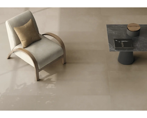 Carreaux de sol lisses de grand format en beige clair dans un salon moderne avec fauteuil et table basse.