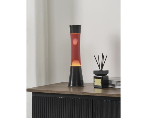Lampe à lave avec liquide rouge et socle noir sur un buffet à côté d'un diffuseur de parfum.