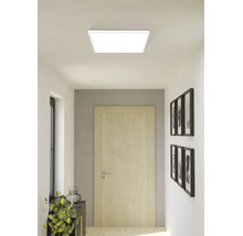 Panneau de plafond LED carré dans un couloir moderne et lumineux avec une porte en bois et des décorations murales.