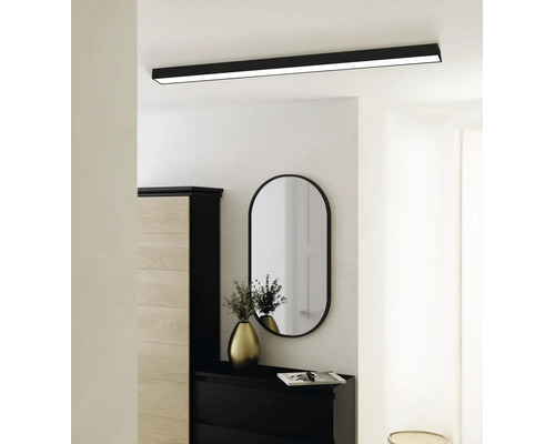 Moderne rechteckige LED Deckenleuchte in Schwarz an einer weissen Decke über einem hellen Flur mit ovalem Spiegel und Kommode.