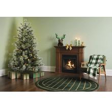 Festliches Wohnzimmer mit künstlichem Weihnachtsbaum, Kamin, Sessel mit Decke und Weihnachtsdekoration auf dunklem Holzboden.