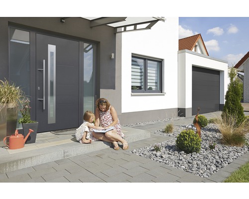 Modernes Haus mit Haustür, Fenster und Garage, Mutter und Kind sitzen davor.