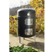 Schwarzer vertikaler Holzkohle-Smoker mit eingebautem Thermometer und zwei Türen auf einer hölzernen Terrasse im Garten.