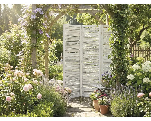 Paravent trois panneaux en bois blanc fait de branches dans un jardin lumineux avec roses, lavande et une arche fleurie.