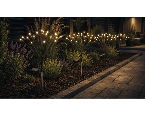 Solar-Gartenleuchten im Feuerwerk-Design mit warmweißen LED-Lampen in einem Gartenbeet neben einem gepflasterten Gartenweg.