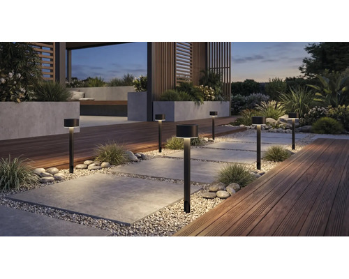 Moderne schwarze Wegeleuchten beleuchten einen organisierten Gartenweg aus Steinplatten und Kies, mit Holzterrasse und Pflanzgefäßen.