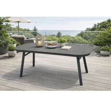 Moderner ovaler Gartentisch auf einer Terrasse mit Holzdeck. Der dunkle Tisch ist dekoriert mit einer Laterne, Obstschale und Pflanze.