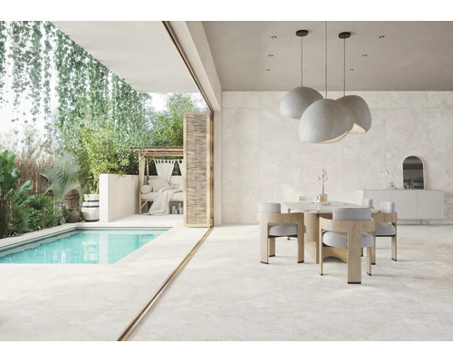 Salle à manger moderne et terrasse avec de grands carreaux aspect pierre naturelle, piscine et végétation luxuriante.
