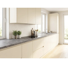 Cuisine moderne et lumineuse avec façades sans poignées couleur crème, plan de travail gris foncé aspect pierre, plaque à induction et évier.