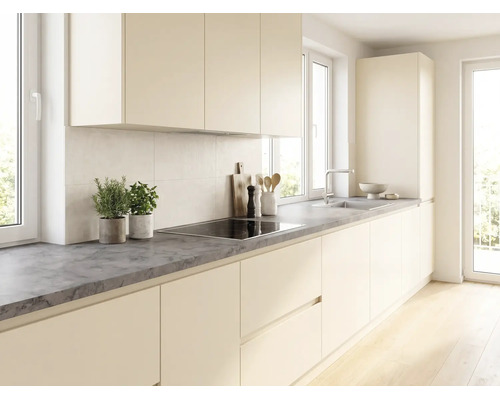 Cuisine moderne et lumineuse avec façades sans poignées couleur crème, plan de travail gris foncé aspect pierre, plaque à induction et évier.