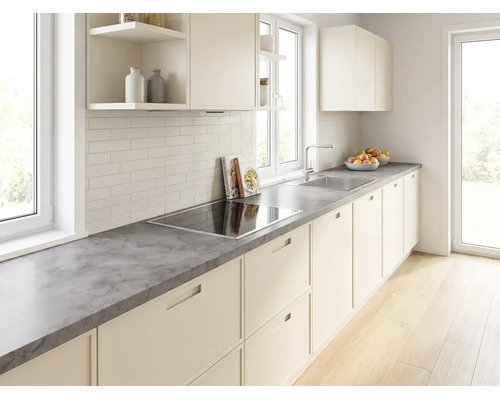 Cuisine intégrée moderne et lumineuse avec plan de travail gris aspect pierre, plaque à induction, évier en inox et crédence en carreaux blancs.