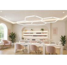 Hell beleuchtetes Nagelstudio mit großflächigen sechseckigen LED-Pendelleuchten, Maniküretischen und Regalen für Nagellack.