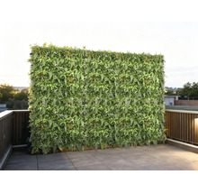 Künstliche Pflanzenwand als Sichtschutz auf einer Terrasse mit Fliesen und Geländer.