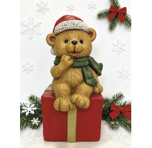 Weihnachtsfigur Teddybär sitzend auf einer roten Geschenkbox mit Weihnachtsmütze und grünem Schal.