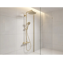 Colonne de douche dorée avec douche de tête, douchette et mitigeur dans une douche carrelée claire avec paroi en verre.