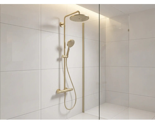 Colonne de douche dorée avec douche de tête, douchette et mitigeur dans une douche carrelée claire avec paroi en verre.