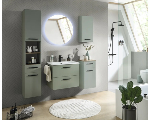 Salle de bain moderne avec meubles vert sauge, meuble sous vasque, armoire haute et miroir LED rond sur un mur carrelé en chevrons.