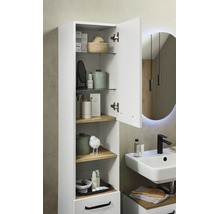 Armoire haute blanche de salle de bain, porte ouverte, tablettes en verre et bois, près d'un lavabo avec robinet noir, style moderne et organisé.