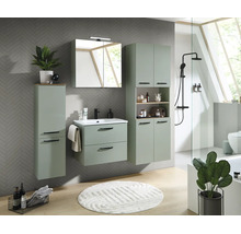 Ensemble de meubles de salle de bain vert sauge avec meuble sous vasque, armoire de toilette et colonnes sur un mur gris à motifs chevrons.