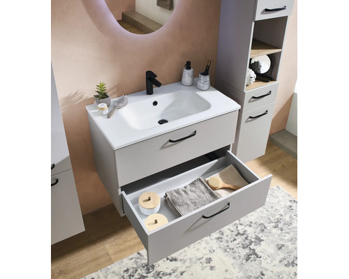 Meuble sous-vasque moderne gris avec lavabo en céramique blanche, robinet noir et tiroir ouvert contenant des serviettes de bain.