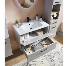 Meuble sous-vasque moderne gris avec lavabo blanc, robinetterie noire et colonne de salle de bain assortie dans une pièce lumineuse.