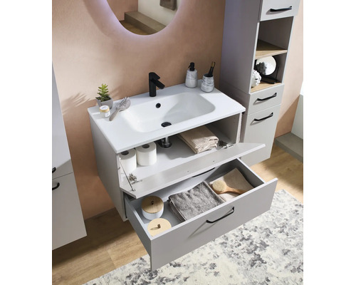 Meuble sous-vasque moderne gris avec lavabo blanc, robinetterie noire et colonne de salle de bain assortie dans une pièce lumineuse.