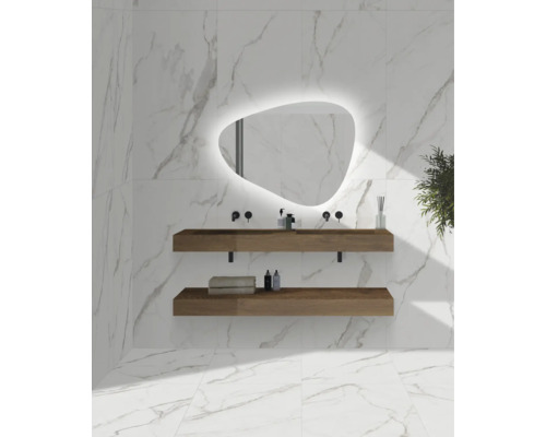 Salle de bains moderne avec carrelage mural aspect marbre blanc, miroir LED de forme organique et deux étagères de lavabo suspendues en bois.