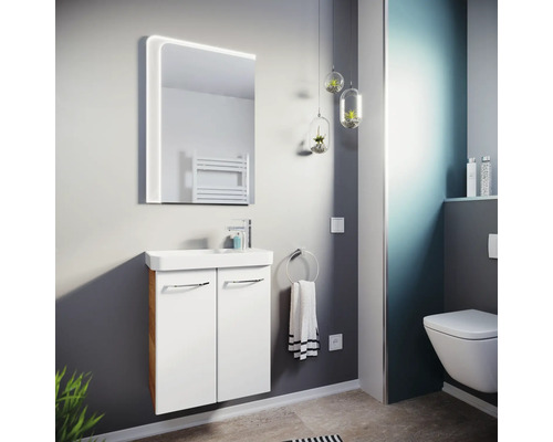 Salle de bains moderne avec meuble sous-vasque blanc, lavabo en céramique, miroir LED et toilette suspendue. Ambiance lumineuse.
