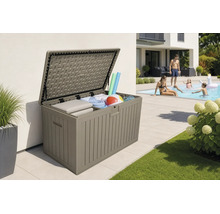 Coffre de jardin ouvert en plastique avec des coussins et des accessoires de piscine sur une terrasse à côté d'une piscine.