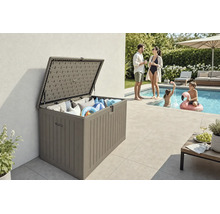 Coffre de jardin ouvert en plastique aspect bois avec coussins et accessoires de piscine sur une terrasse à côté d'une piscine.