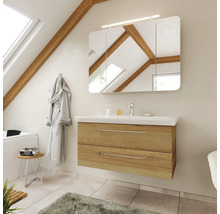 Meuble de salle de bains moderne aspect chêne avec lavabo blanc, armoire de toilette à trois portes et éclairage sous un toit en pente.