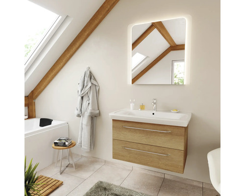 Modernes Badezimmer mit hängendem Waschbeckenunterschrank in Holzoptik, weißem Waschtisch und beleuchtetem Spiegel unter einer Dachschräge.