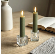 Bougies LED vertes dans des bougeoirs carrés en verre sur une table en bois dans un environnement lumineux et organisé avec livre et vase.