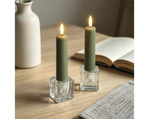 Bougies LED vertes dans des bougeoirs carrés en verre sur une table en bois dans un environnement lumineux et organisé avec livre et vase.