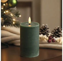 Bougie pilier LED avec surface texturée et flamme vacillante dans un décor de Noël avec sapin et pommes de pin.