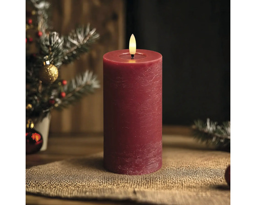 Rote LED-Stumpenkerze mit rustikaler Oberfläche und täuschend echter Flamme in einer weihnachtlichen Dekoration.