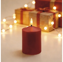 LED-Stumpenkerze rot in festlicher Szene mit Geschenkkartons und einer Lichterkette.