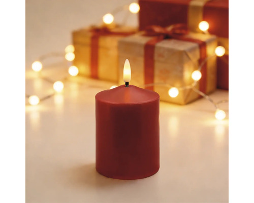 LED-Stumpenkerze rot in festlicher Szene mit Geschenkkartons und einer Lichterkette.