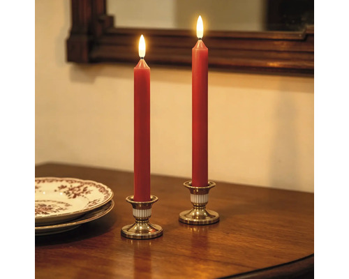 Zwei rote LED-Stabkerzen in goldfarbenen Kerzenhaltern auf einem dunklen Holztisch in warmer Atmosphäre.