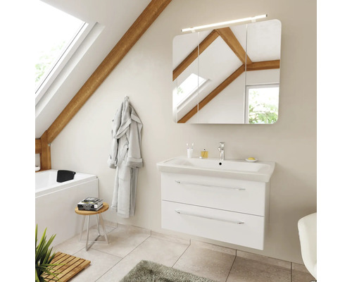 Badezimmer mit weissem Waschtischunterschrank, Keramikwaschbecken und dreitürigem Spiegelschrank mit Beleuchtung in einem hellen Dachgeschossraum.